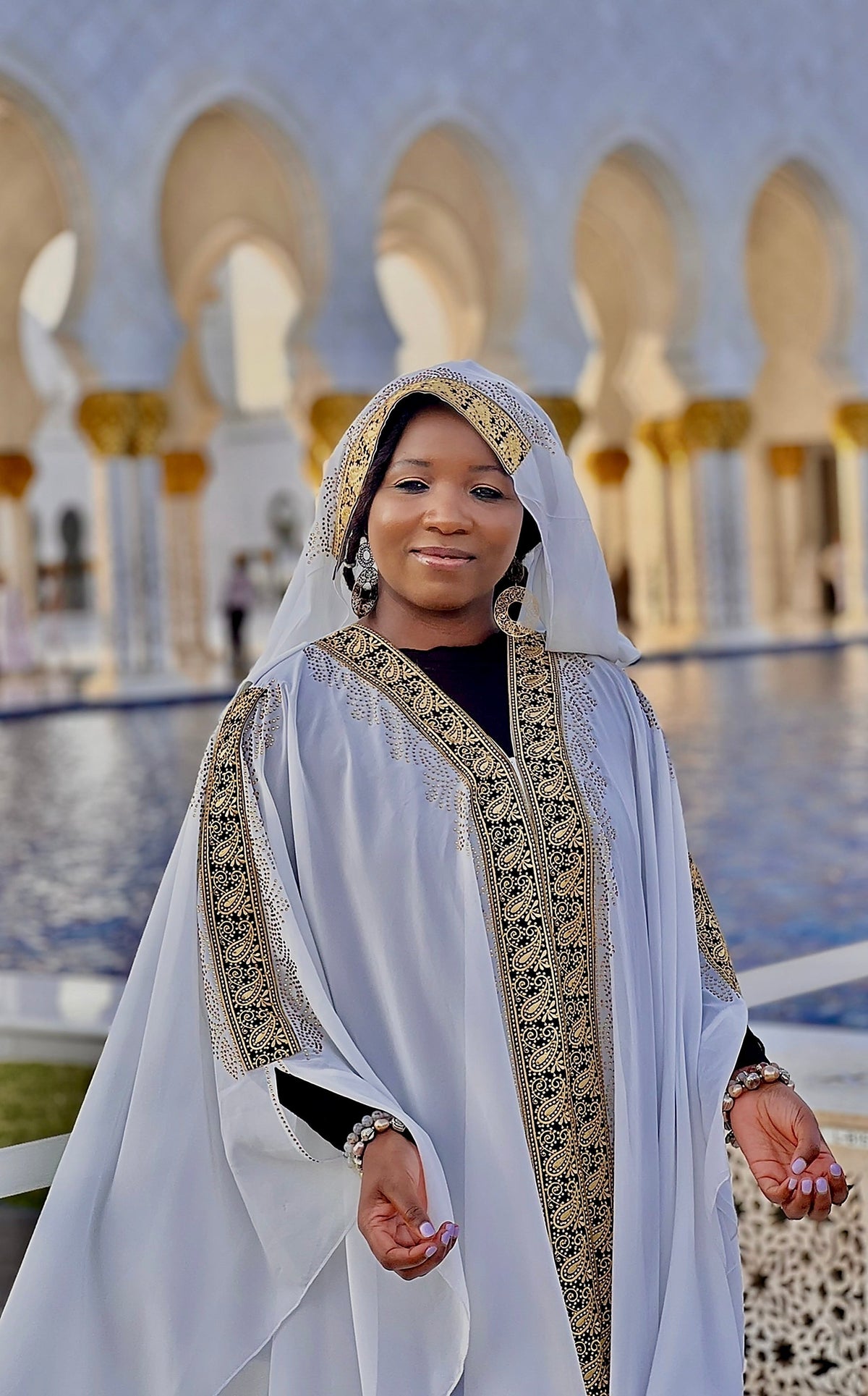 Theresa Rézeau at the Sheikh Zayed Grand Mosque in Abu Dhabi, standing in the marble courtyard surrounded by the mosque’s white domes and Islamic architecture.